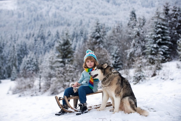 Juegos activos de invierno al aire libre para niños con perro husky feliz navidad concepto de vacaciones niño disfrutando...