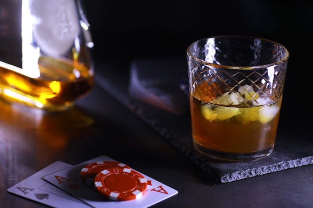 Juegos de cartas de juego por dinero. Póquer Texas Hold'em. Cartas en mano, fichas de juego, una baraja de cartas de alcohol en un vaso.