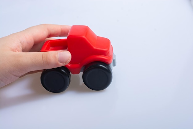 Juegos de manos con camión de juguete sobre fondo blanco.