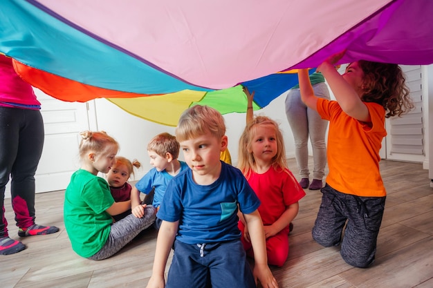 Juegos organizados de creación de equipos para niños que usan el dosel del arco iris