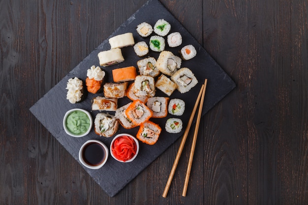 Juegos de rollos de sushi con pescado, arroz, queso crema y verduras.