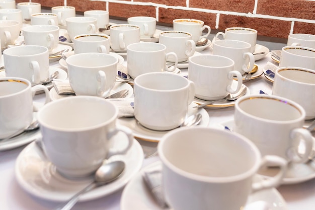 Juegos de tazas de té con bolsitas de té y cuchara de metal. Fila de tazas blancas preparándose para un banquete