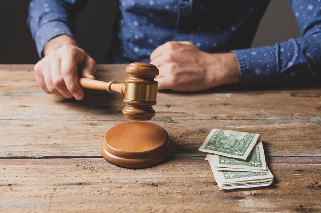 Foto el juez golpea con un martillo y hay dinero sobre la mesa.