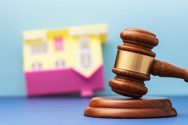 Juez martillo y casa de juguete al revés en la mesa concepto de arresto inmobiliario