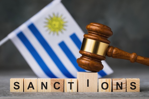 Juez martillo cubos de madera con el concepto de bandera de texto sobre el tema de las sanciones en Uruguay