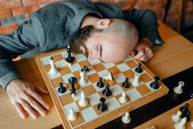 Jugador de ajedrez masculino cansado durmiendo en el tablero.