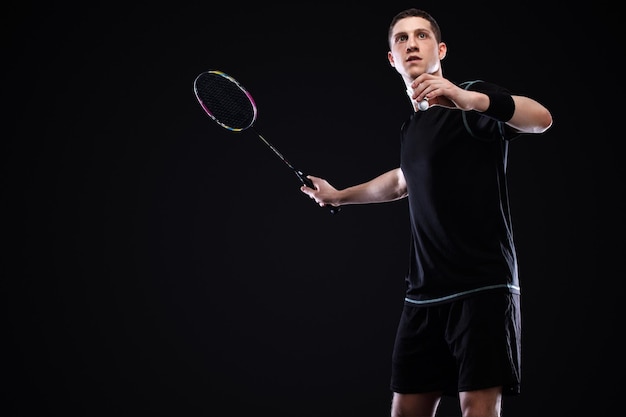 Jugador de bádminton en ropa deportiva con raqueta y volante sobre fondo negro Deportes individuales Recreación deportiva