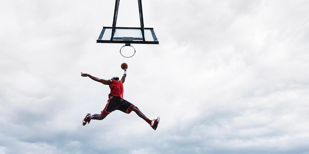 Jugador de baloncesto callejero haciendo una poderosa volcada en la cancha