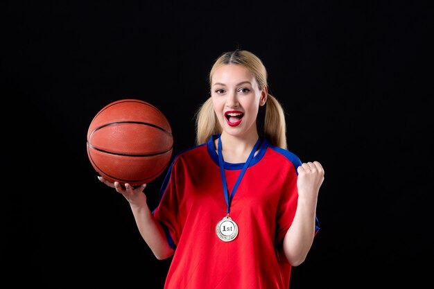 Jugador de baloncesto femenino con balón y medalla de oro sobre fondo negro ganador del trofeo de atleta