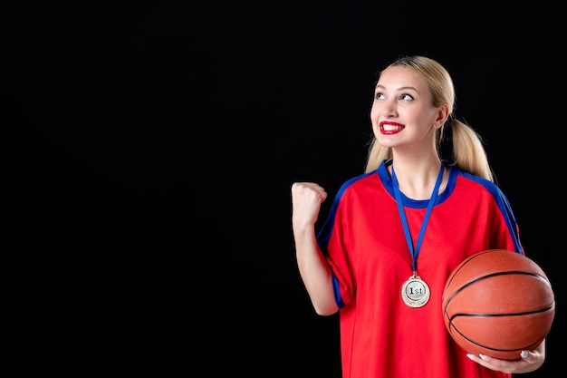 Jugador de baloncesto femenino con balón y medalla de oro sobre fondo negro trofeo ganador atleta