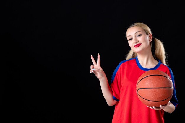 Jugador de baloncesto femenino con balón sobre el fondo negro aislado atleta jugar juego de acción