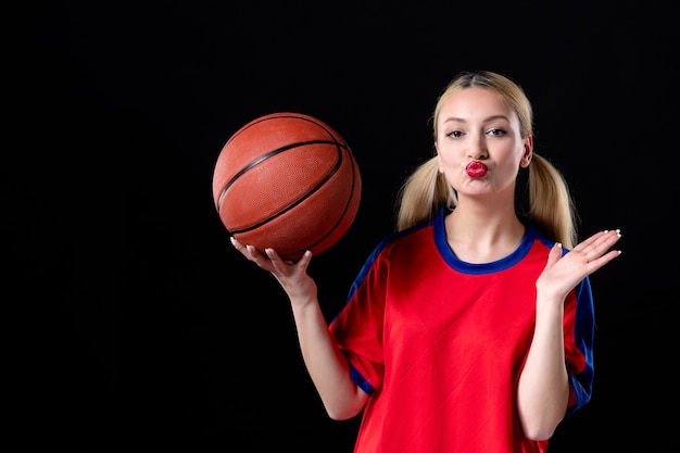 Jugador de baloncesto femenino en ropa deportiva con balón sobre el fondo negro juego de ejercicio atleta