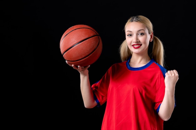 Jugador de baloncesto femenino en ropa deportiva con balón sobre fondo negro juego de ejercicios