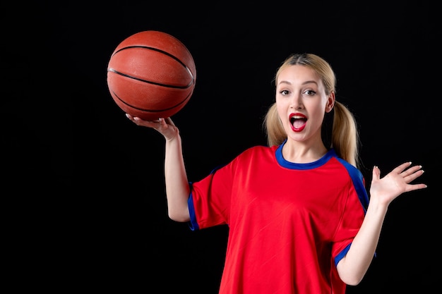 Jugador de baloncesto femenino en ropa deportiva con balón sobre fondo negro juegos de ejercicio atleta