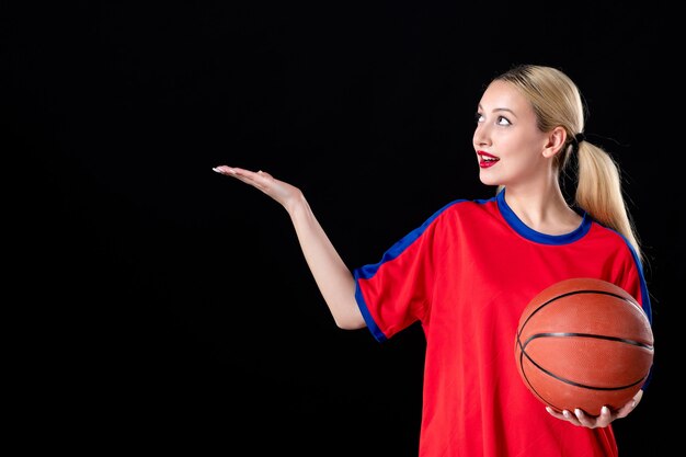 Jugador de baloncesto femenino en ropa deportiva con pelota sobre fondo negro juego de atletas juegan