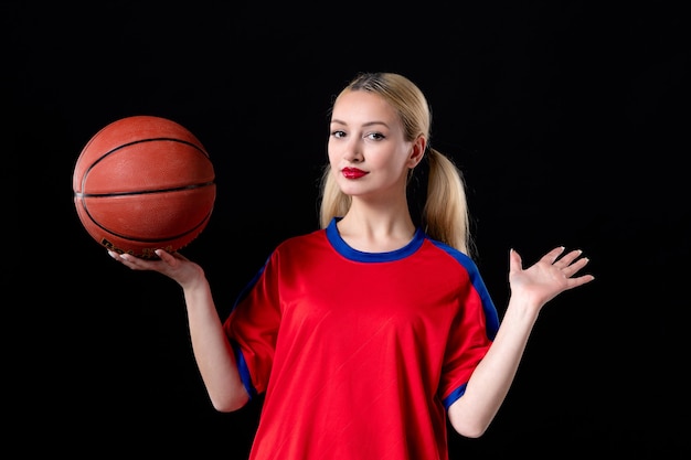 Jugador de baloncesto femenino en ropa deportiva con pelota sobre fondo negro juegos de ejercicio de atleta