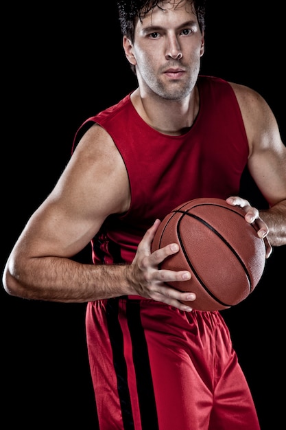 Jugador de baloncesto con una pelota en sus manos y un uniforme rojo. estudio fotografico.