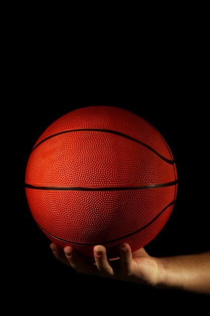 Jugador de baloncesto sosteniendo la pelota sobre fondo oscuro