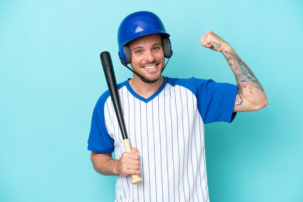 Jugador de béisbol con casco y bate aislado en fondo azul haciendo un gesto fuerte