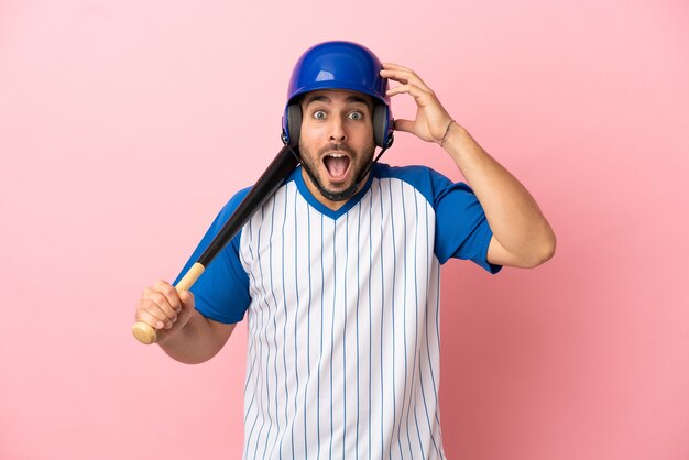 Jugador de béisbol con casco y bate aislado sobre fondo rosa con expresión de sorpresa