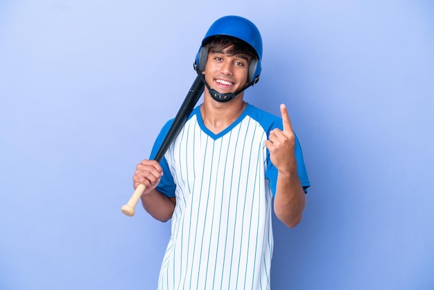 Jugador de béisbol caucásico con casco y bate aislado sobre fondo azul haciendo el gesto de venir