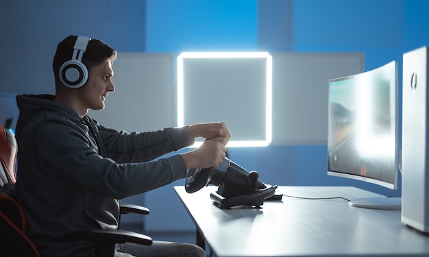 El jugador de chico con auriculares jugando videojuegos en su computadora personal