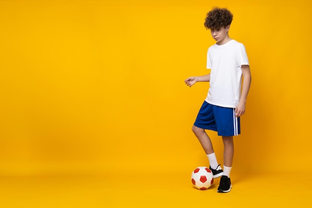 Foto jugador de fútbol adolescente en un fondo amarillo