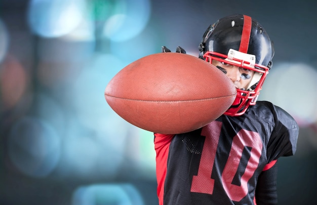 Jugador de fútbol americano con el balón aislado sobre un fondo oscuro