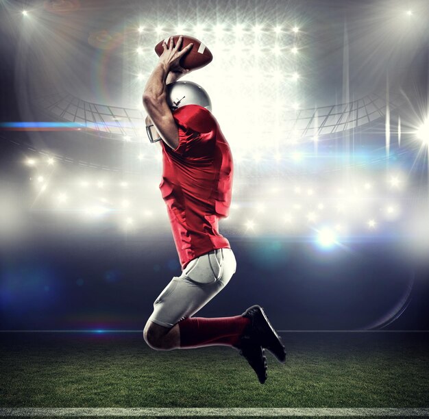 Foto jugador de fútbol americano con camiseta roja saltando contra el estadio de fútbol americano