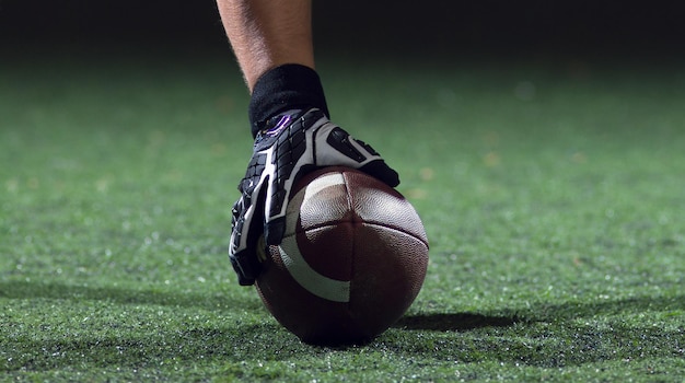 Jugador de fútbol americano comenzando un partido de fútbol en el campo de fútbol americano por la noche