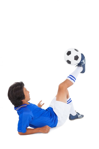 Jugador de fútbol en azul pateando la pelota