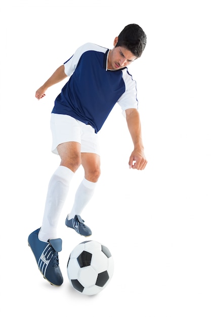 Jugador de fútbol en azul pateando la pelota