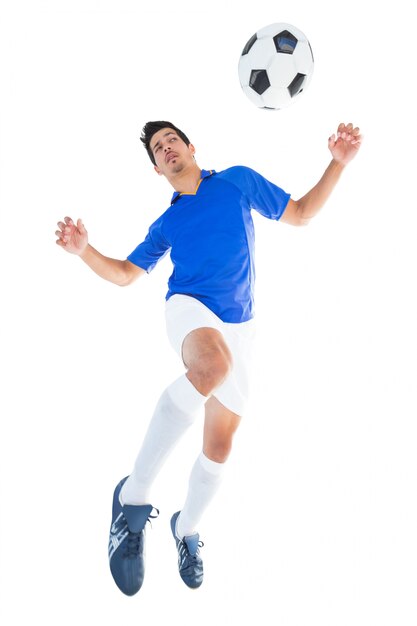 Jugador de fútbol en azul saltando a la pelota