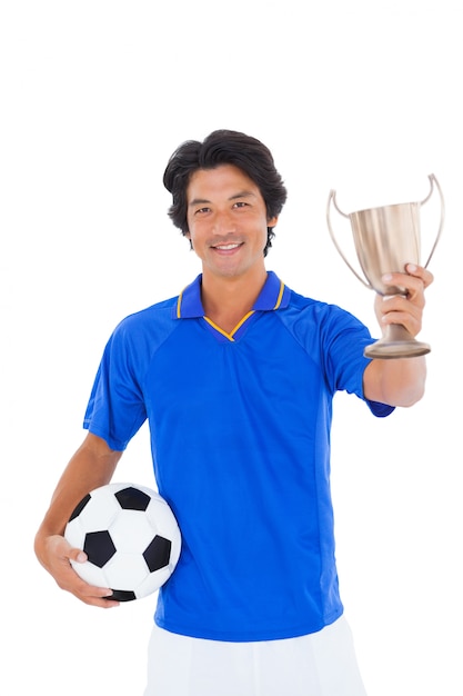 Jugador de fútbol en azul sosteniendo la taza de ganadores