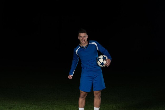 Jugador de fútbol de hombre celebrando la victoria en uniforme azul sobre fondo negro