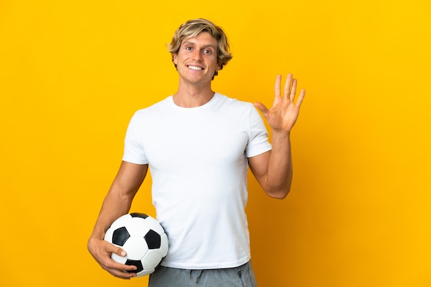 Jugador de fútbol inglés sobre amarillo saludando con la mano con expresión feliz