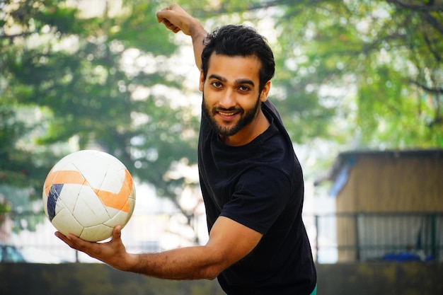 Foto jugador de fútbol joven con imagen de bola en la mano