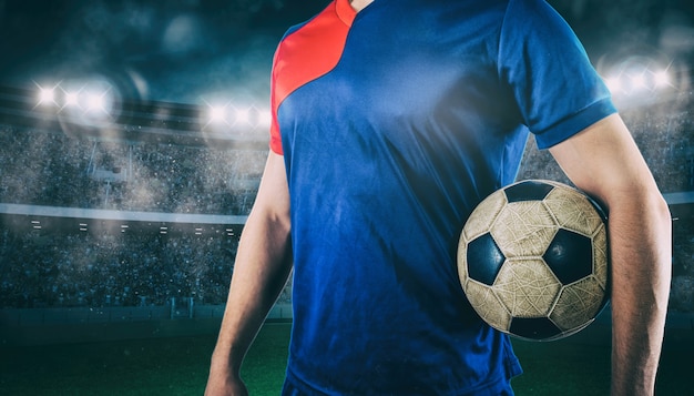 Jugador de fútbol listo para jugar con balón en sus manos en el estadio