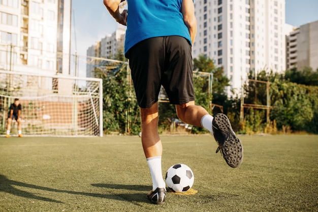 Jugador de fútbol masculino golpea la pelota en el campo. Futbolista en el estadio al aire libre, entrenamiento antes del juego, entrenamiento de fútbol