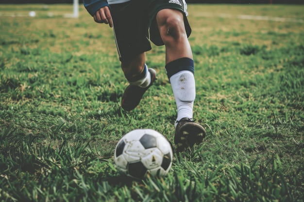 Foto jugador de fútbol masculino con la pelota en el campo de hierba clse en la pelota y los pies generativo ai