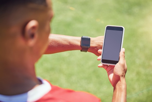 Jugador de fútbol de pantalla verde y teléfono en el campo con tecnología de reloj inteligente o maqueta en la aplicación digital móvil Hombre jugador de fútbol o teléfono inteligente en la web de redes sociales o red 5g en un juego de entrenamiento o partido