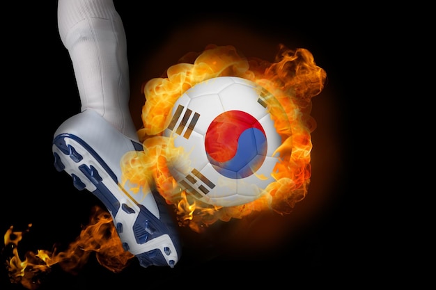 Jugador de fútbol pateando la pelota en llamas de la República de Corea contra el negro