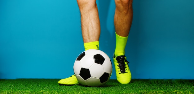 Jugador de fútbol con pelota sobre la hierba verde y azul