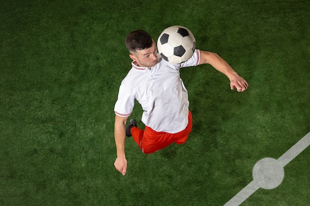 Jugador de fútbol que aborda la bola sobre fondo de hierba verde