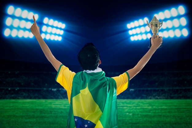 Foto jugador de fútbol sosteniendo el trofeo en el campo