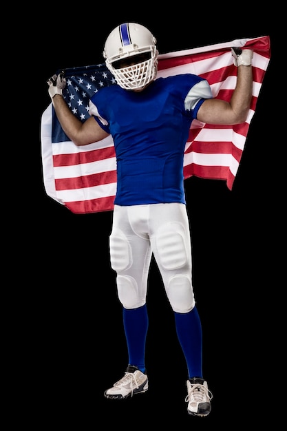 Jugador de fútbol con un uniforme azul y una bandera americana, sobre una pared negra