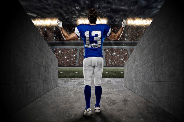 Jugador de fútbol con uniforme azul saliendo de un túnel del estadio