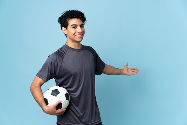 Jugador de fútbol venezolano hombre sobre antecedentes aislados extendiendo las manos hacia el lado para invitar a venir