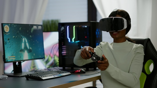 Jugador ganador con joystick jugando videojuegos en la sala de juegos con realidad virtual. Jugador profesional profesional que transmite videojuegos en línea con nuevos gráficos en una computadora potente que utiliza equipos modernos.