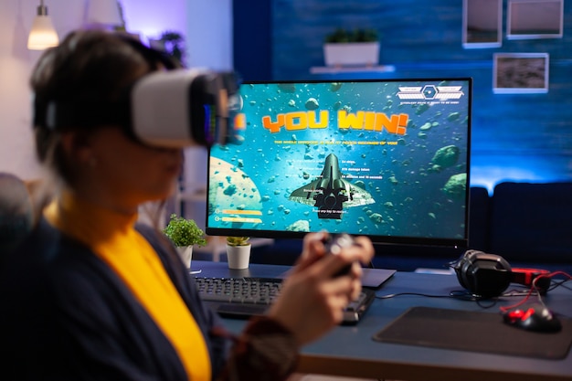 Jugador ganador jugando videojuegos de disparos espaciales con casco de realidad virtual durante el campeonato. Cibernético virtual de transmisión en línea durante el torneo de juego utilizando tecnología de red inalámbrica